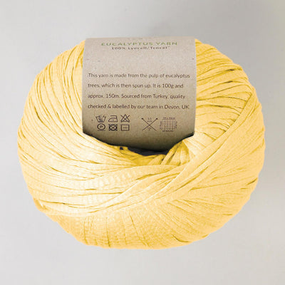 Yellow yarn ball with a label on a light gray background