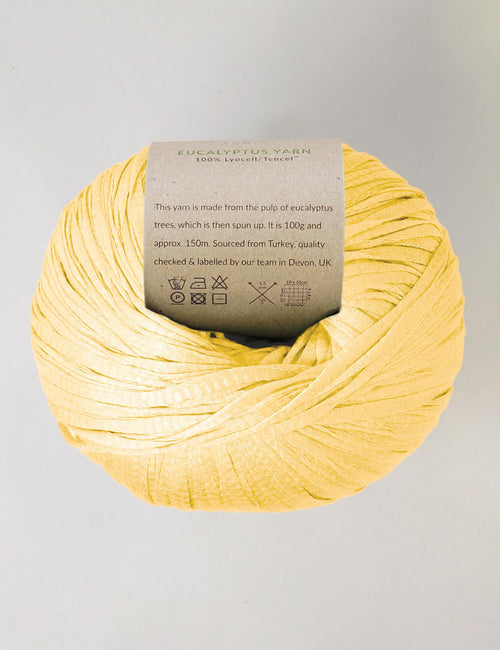 Yellow yarn ball with a label on a light gray background