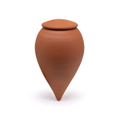 Small terracotta olla pot on it's side with the lid next to it. 