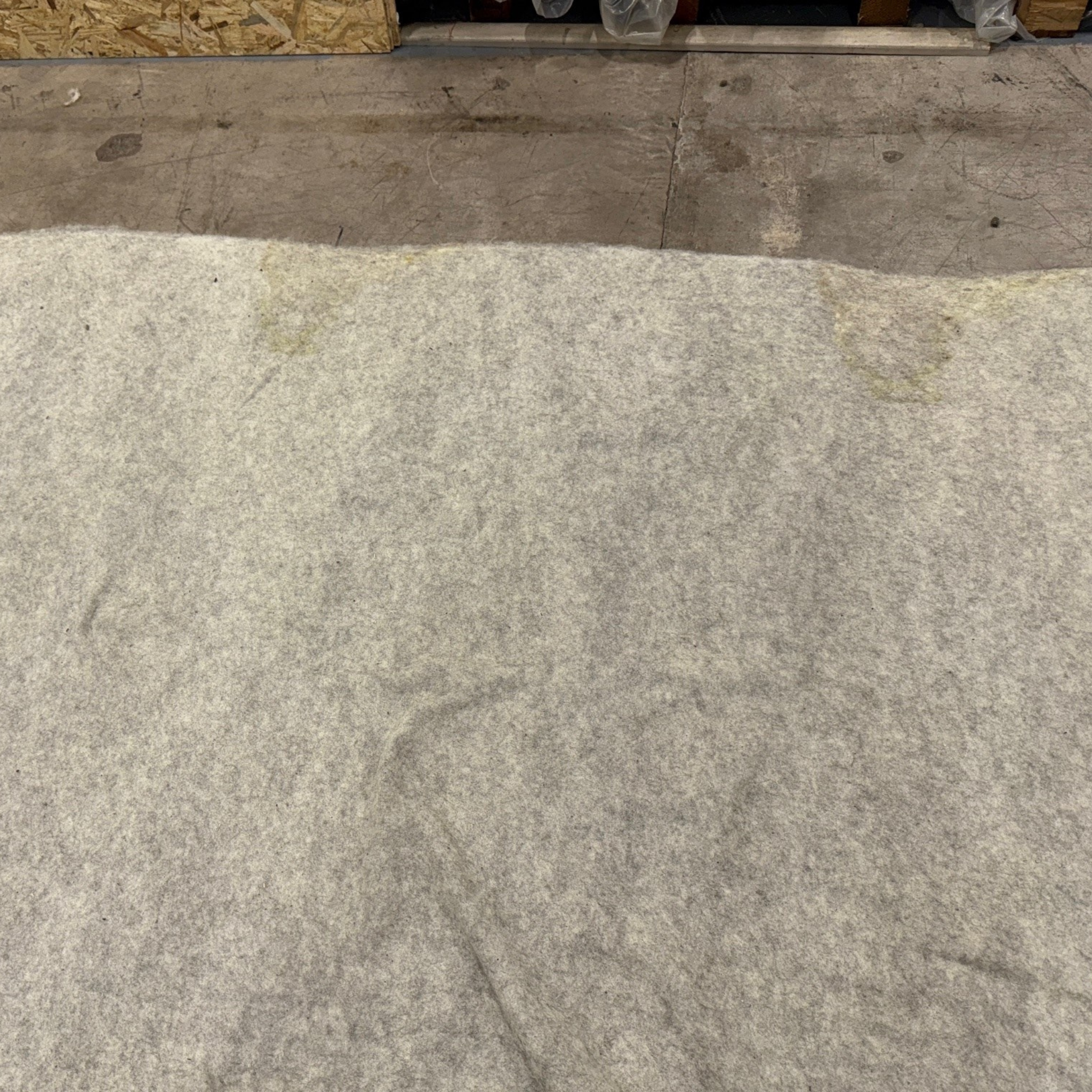 Sheep wool garden fleece on warehouse floor, showing watermarks. 