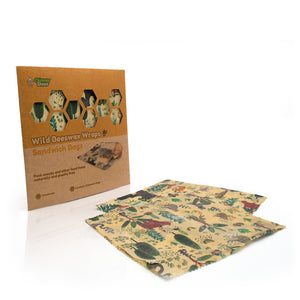 Wild Bees Bakery Wild Beeswax Wraps Sandwich Bags, featuring a brown kraft paper sleeve and two reusable fabric wraps with a colorful jungle animal print on a white background.