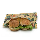 Two subway sandwiches wrapped in a decorative reusable beeswax wrap fabric sandwich bag with a jungle animal print, set against a plain white background.