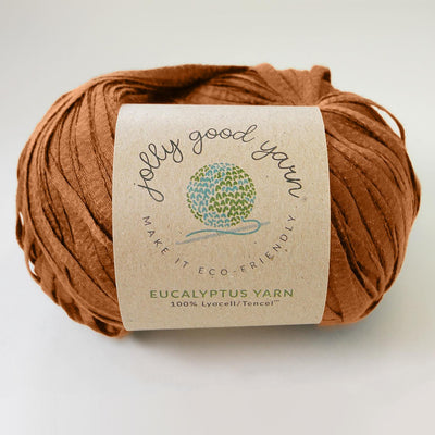 Yellow yarn ball with a label on a light gray background