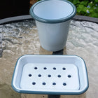 White enamel soap dish and mug with grey rim on glass table