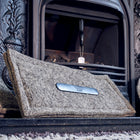 A grey wool Chimney Sheep chimney draught blocker in front of a fireplace.